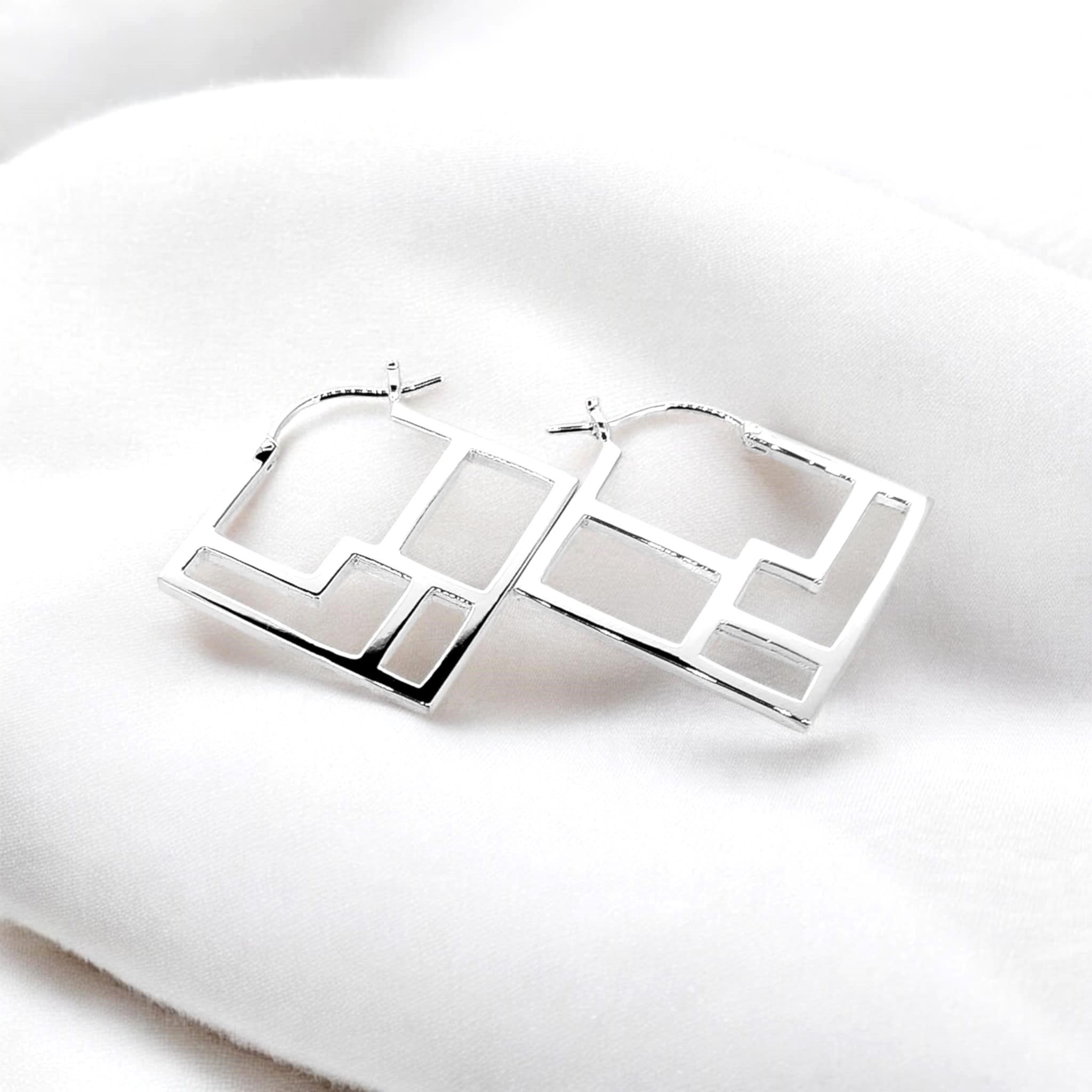 Square sterling silver earrings with a symmetrical web of lines creating an intricate and eye-catching design