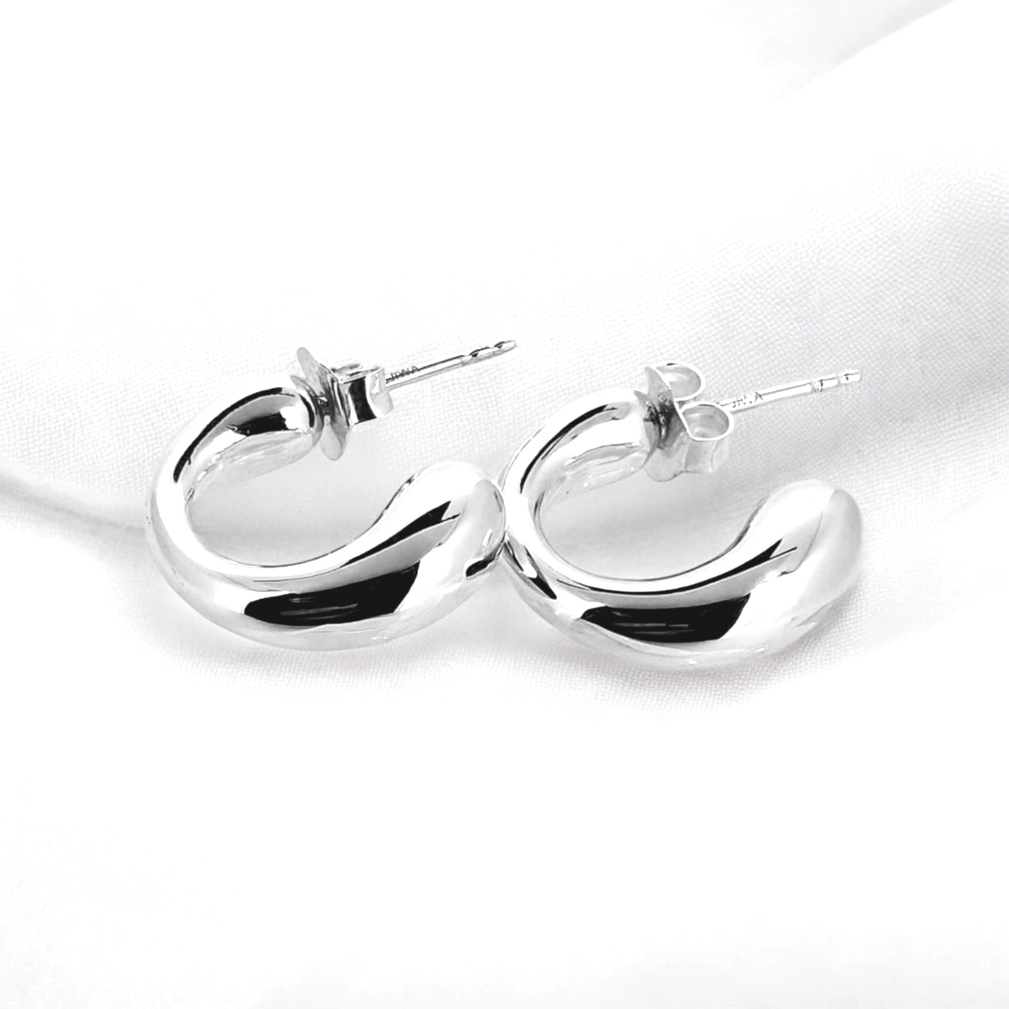 Sterling silver opened sleeper earrings have a stretched look tapering gracefully from a thinner top to a wider base