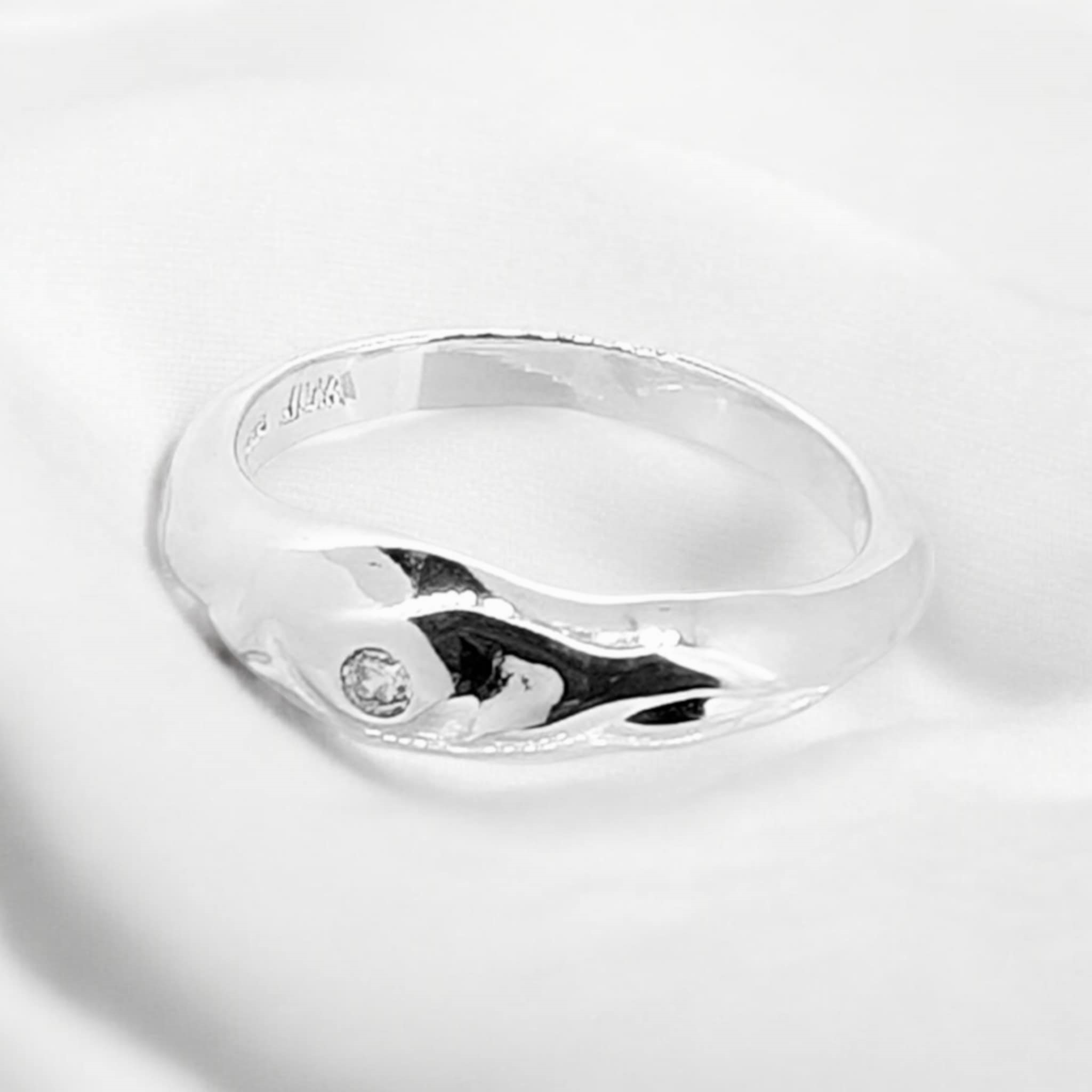 This mottled sterling silver band ring exudes a unique charm with its texture & single zirconia
