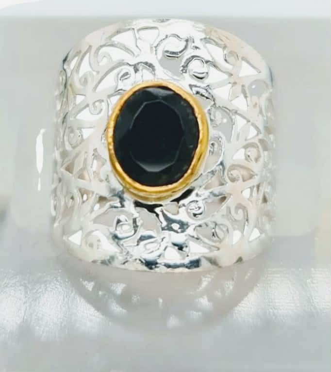 A polished black onyx known for its grounding and protective qualities anchors the design in ths large silver web ring